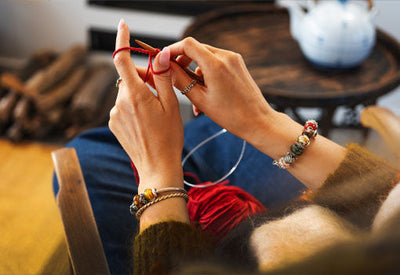 Creative crafting in a cozy environment, knitting with red yarn and Trollbeads autumn jewellery on