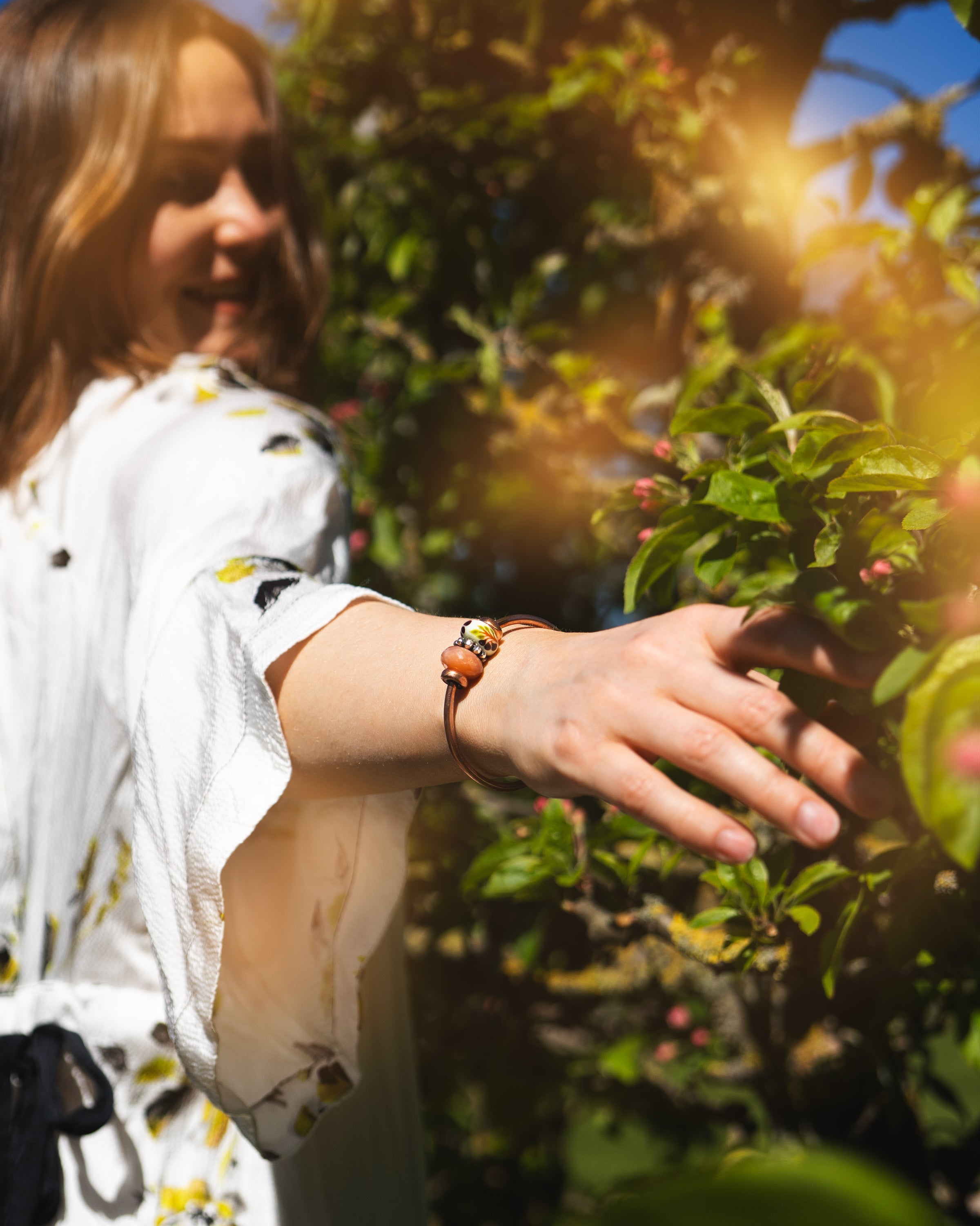 Model in garden wearing a copper bangle with beads