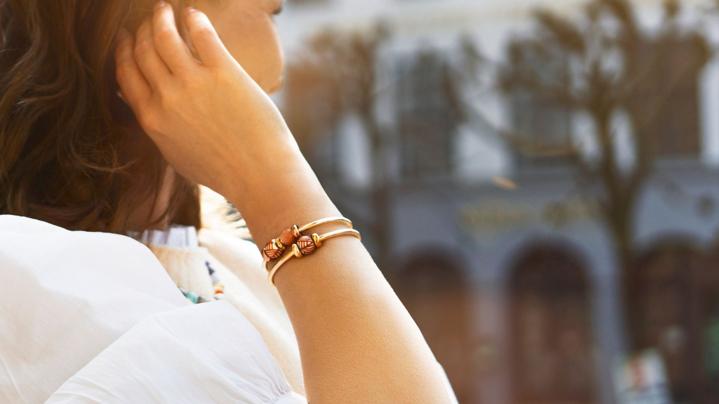 Woman wearing two gold plated bangles with barrel beads